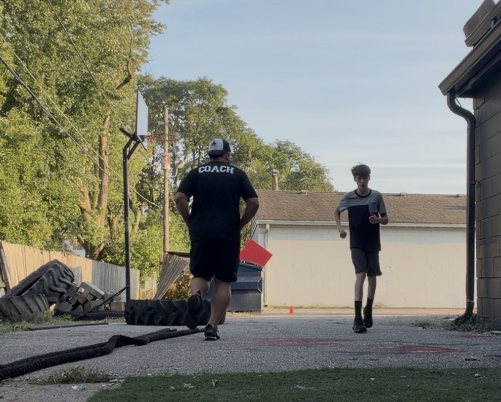 Coach and client running conditioning intervals past battle ropes and tires